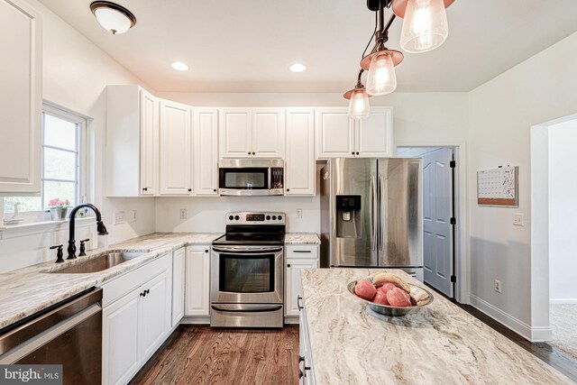 kitchen with light stone countertops, dark wood-style floors, white cabinetry, a sink, and appliances with stainless steel finishes