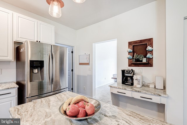 kitchen featuring stainless steel refrigerator with ice dispenser, white cabinetry, and light stone countertops