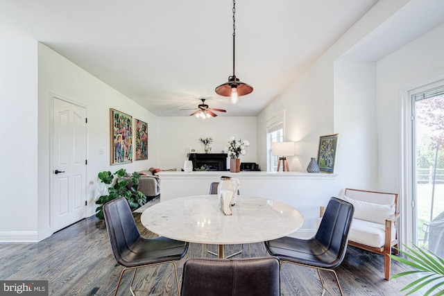 dining area with baseboards, a fireplace, a ceiling fan, and wood finished floors