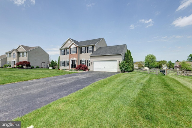 colonial-style house with a garage, a front lawn, aphalt driveway, and fence