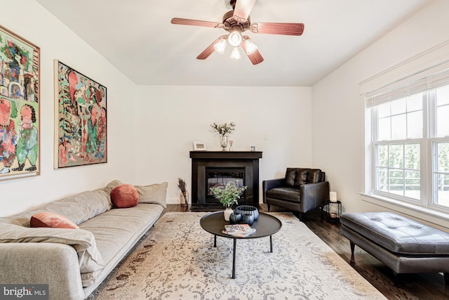 living room featuring a glass covered fireplace, a ceiling fan, and wood finished floors
