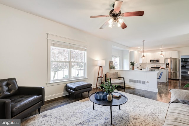 living area with baseboards, ceiling fan, dark wood finished floors, and visible vents