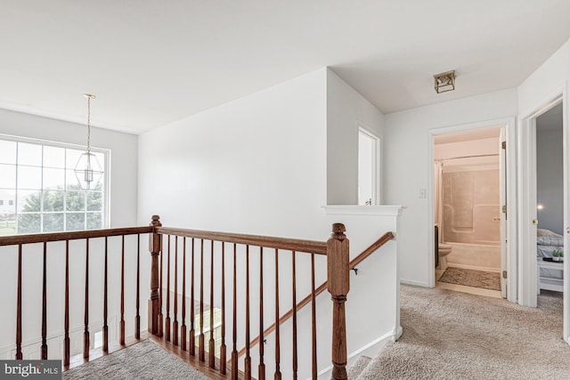 hall featuring baseboards, carpet flooring, and an upstairs landing