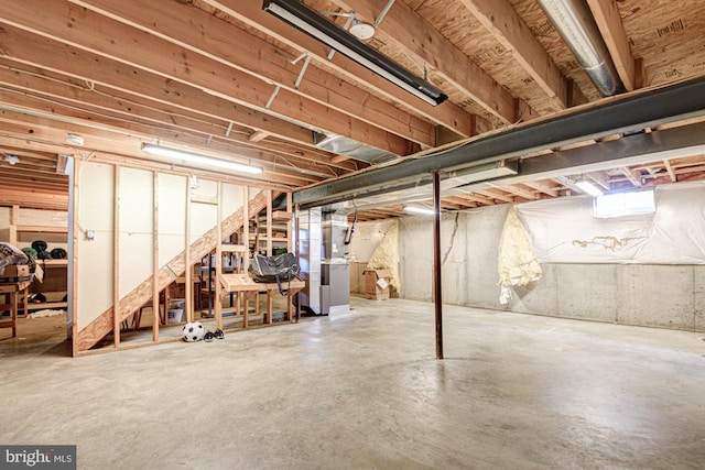 unfinished basement featuring heating unit and stairs