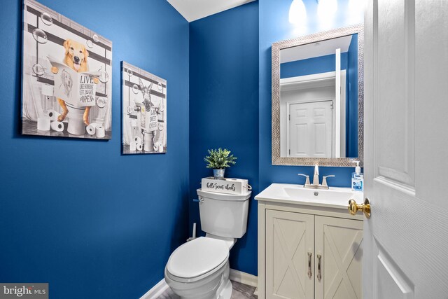 bathroom with baseboards, vanity, and toilet