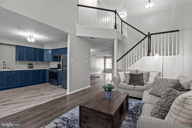 living area with a towering ceiling, arched walkways, stairway, baseboards, and light wood-style flooring