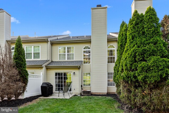 rear view of property with fence, cooling unit, a patio, a chimney, and a yard