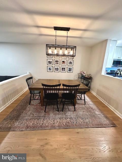 dining area with baseboards, wood finished floors, and an inviting chandelier