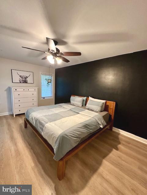 bedroom with a ceiling fan, baseboards, and light wood-style floors