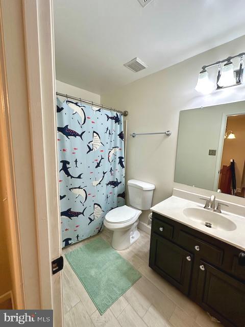 full bathroom featuring toilet, visible vents, curtained shower, and vanity