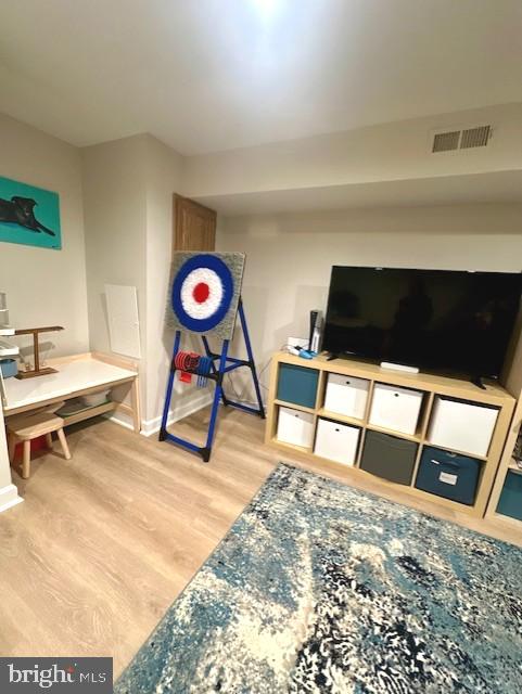 recreation room with baseboards, wood finished floors, and visible vents