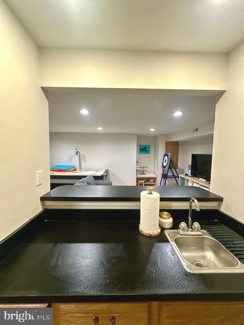 kitchen with brown cabinets, dark countertops, a sink, recessed lighting, and baseboards