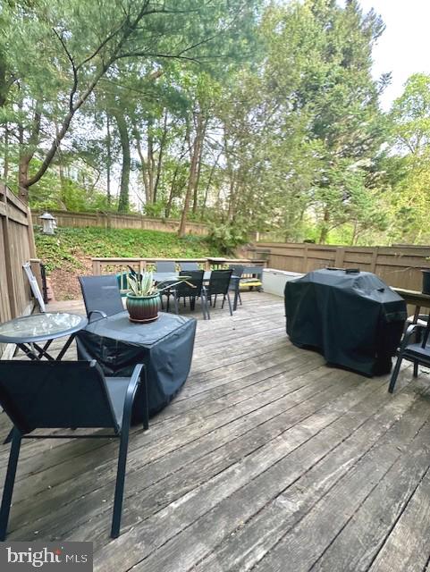 wooden terrace featuring a fenced backyard, outdoor dining space, and grilling area