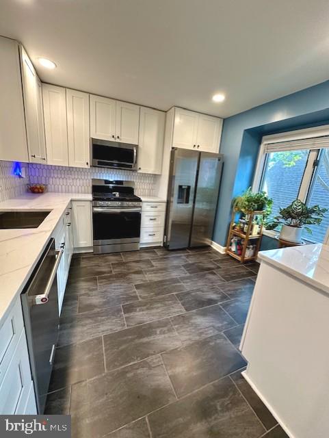 kitchen with white cabinetry, appliances with stainless steel finishes, and decorative backsplash