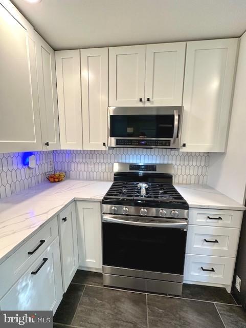 kitchen featuring light stone counters, white cabinets, and stainless steel appliances