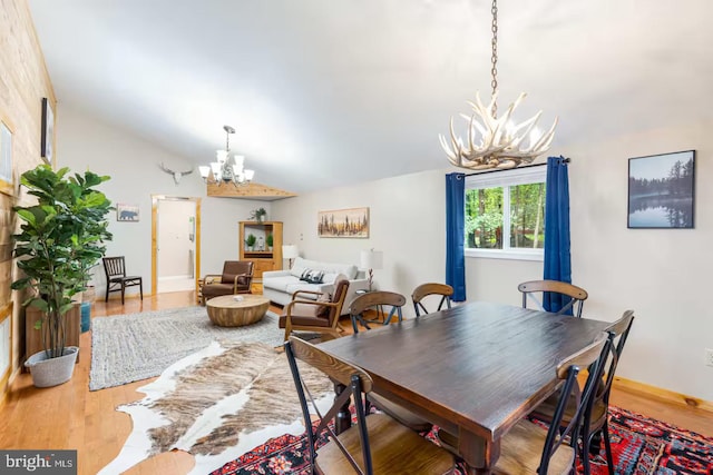 dining area featuring an inviting chandelier, baseboards, lofted ceiling, and wood finished floors