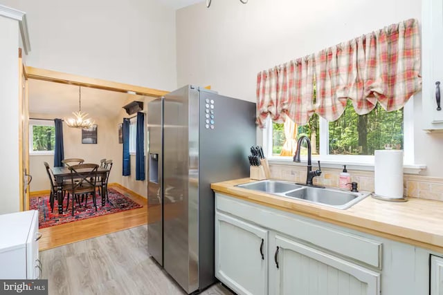 kitchen featuring an inviting chandelier, a sink, light countertops, and stainless steel fridge with ice dispenser