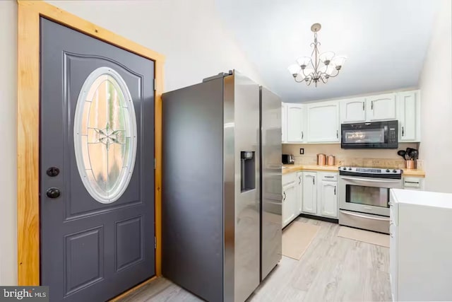kitchen with an inviting chandelier, light countertops, white cabinetry, light wood-style flooring, and appliances with stainless steel finishes