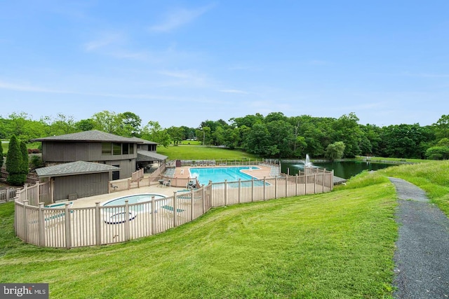 pool with a lawn, fence, a water view, and a patio area