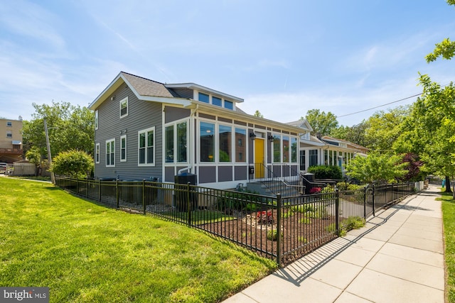 rear view of house featuring a lawn and fence