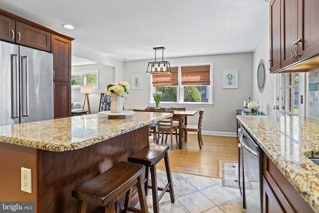 kitchen featuring a center island, light stone counters, baseboards, a breakfast bar, and stainless steel appliances