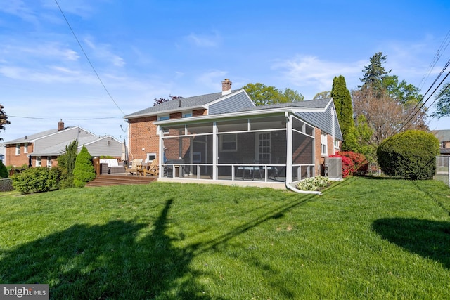 rear view of house with a lawn, brick siding, and a sunroom