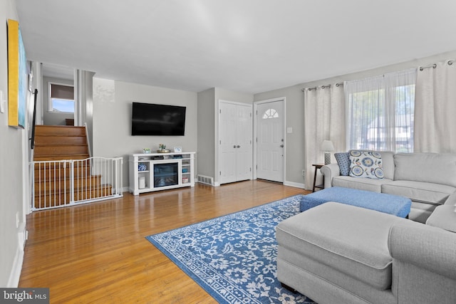 living room featuring baseboards, a healthy amount of sunlight, and wood finished floors