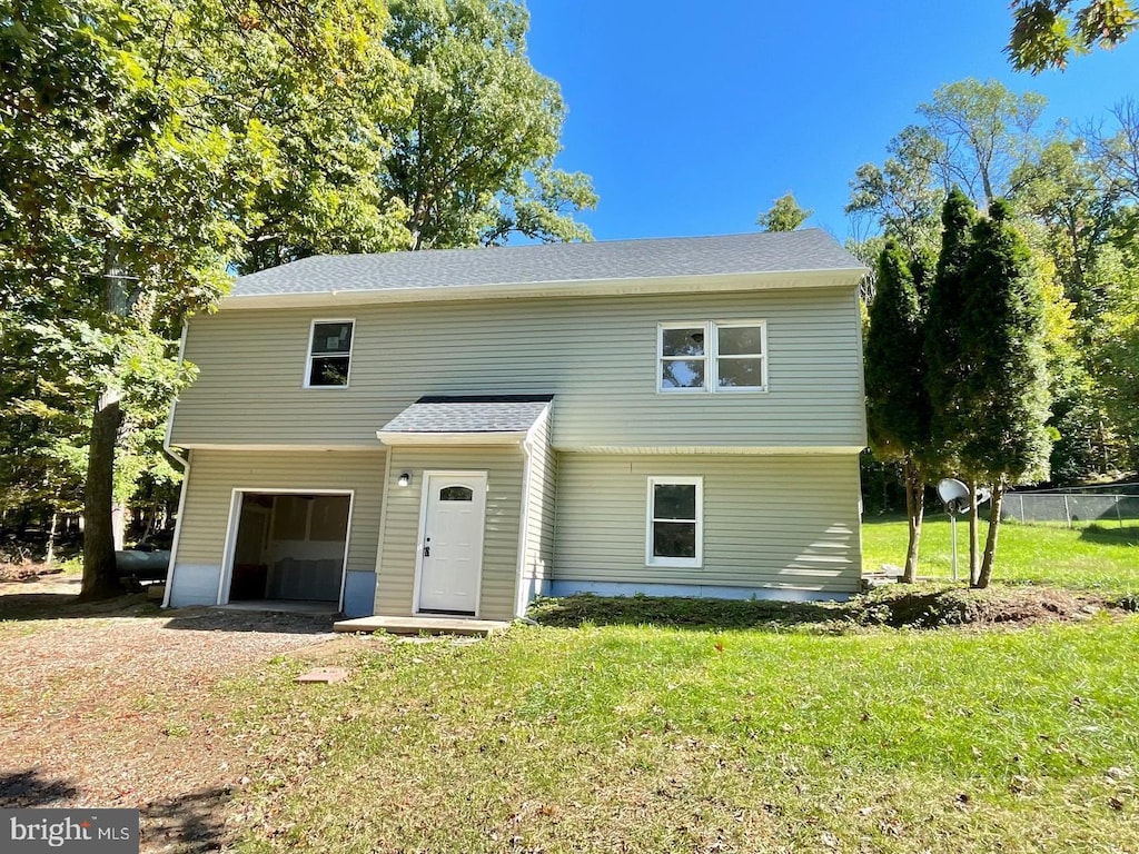 view of front of house with fence, an attached garage, a shingled roof, and a front lawn