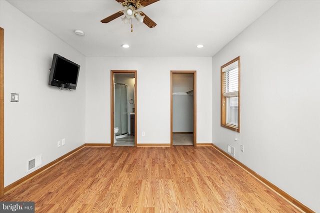 unfurnished bedroom with light wood-style floors, baseboards, a walk in closet, and visible vents