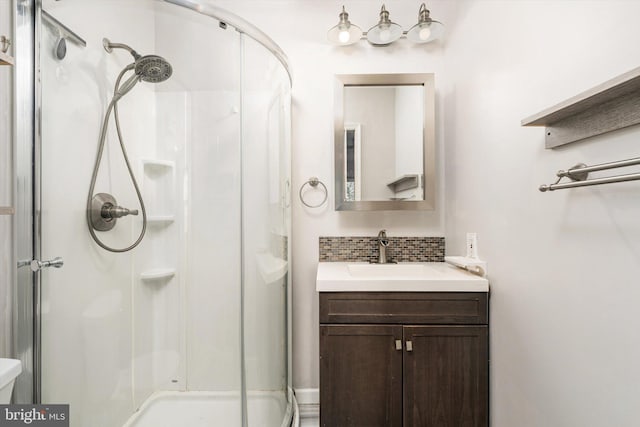 full bath with vanity, decorative backsplash, a stall shower, and toilet