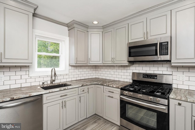 kitchen with a sink, tasteful backsplash, light stone countertops, and stainless steel appliances