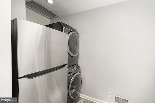 washroom featuring laundry area, light wood-style floors, baseboards, visible vents, and stacked washer and clothes dryer