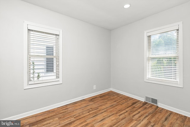 empty room with baseboards, recessed lighting, wood finished floors, and visible vents