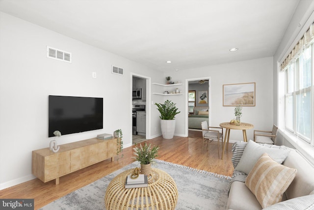 living area with visible vents, recessed lighting, baseboards, and wood finished floors