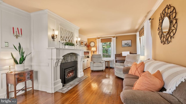 477 Linton Hill Rd, Newtown, PA 18940 - living room featuring radiator heating unit, crown molding, wood-type flooring, and a warm lit fireplace