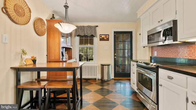 477 Linton Hill Rd, Newtown, PA 18940 - kitchen with dark countertops, radiator heating unit, white cabinets, dark floors, and appliances with stainless steel finishes