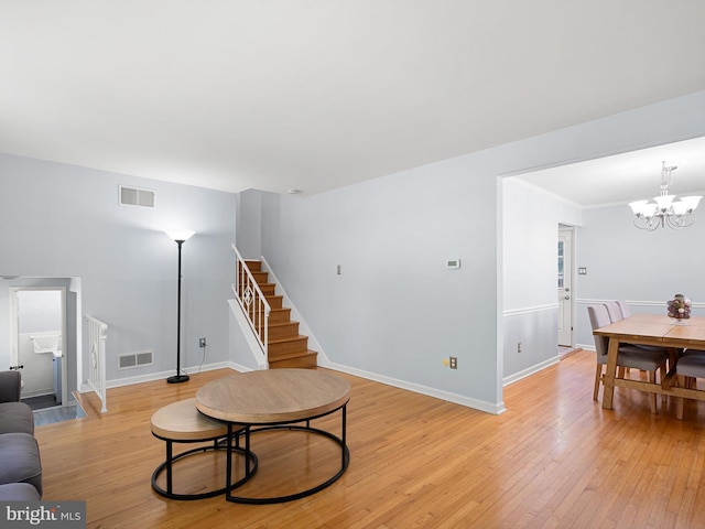 living area with a chandelier, visible vents, light wood-style flooring, and stairway