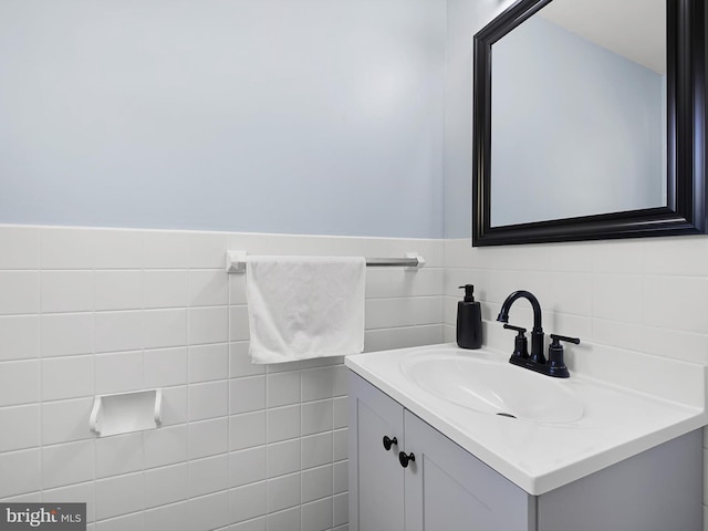 bathroom featuring wainscoting, tile walls, and vanity