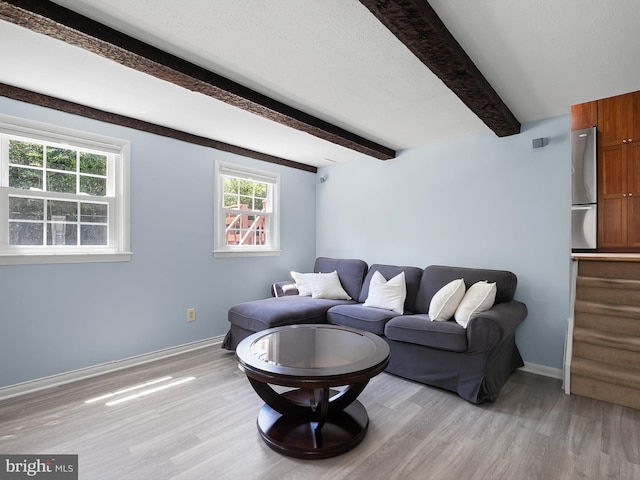 living area with baseboards, light wood finished floors, and beamed ceiling