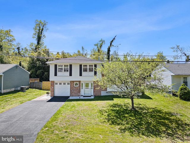 colonial inspired home with a front yard, a garage, brick siding, fence, and aphalt driveway