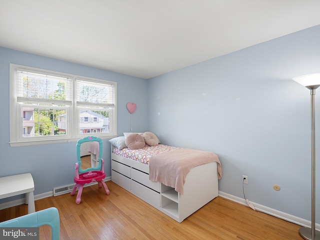 bedroom with baseboards, visible vents, and light wood-style floors