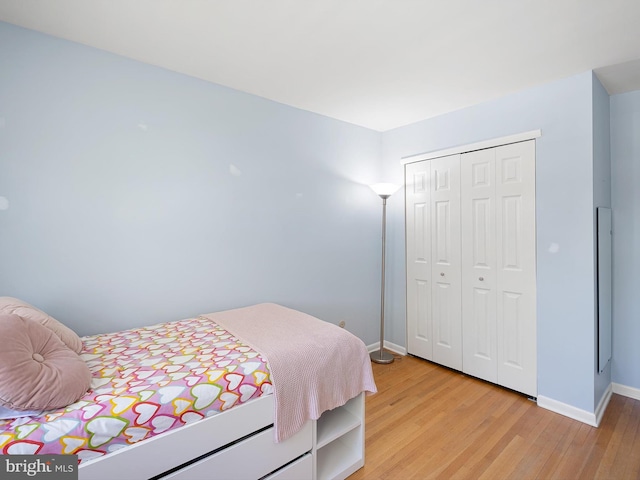 bedroom featuring light wood-style floors, baseboards, and a closet