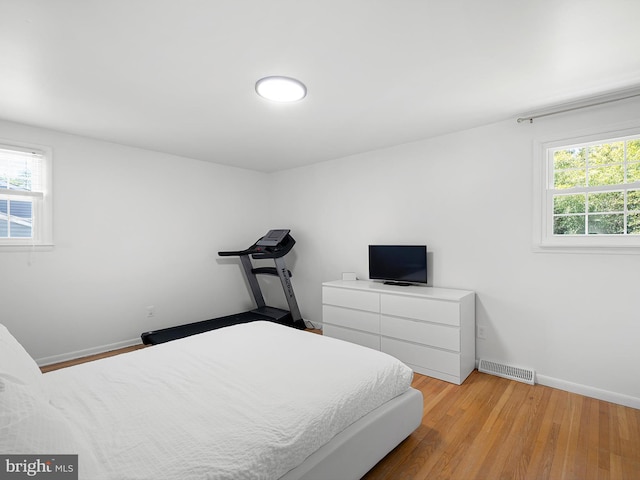 bedroom with baseboards, wood finished floors, and visible vents