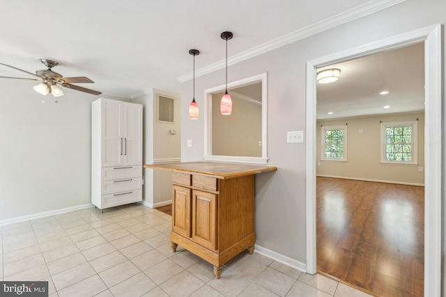 kitchen featuring baseboards, ornamental molding, and decorative light fixtures