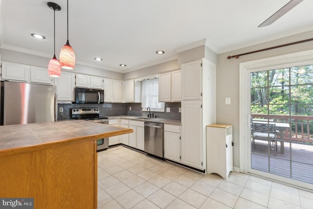 kitchen with decorative backsplash, a sink, ornamental molding, tile counters, and stainless steel appliances