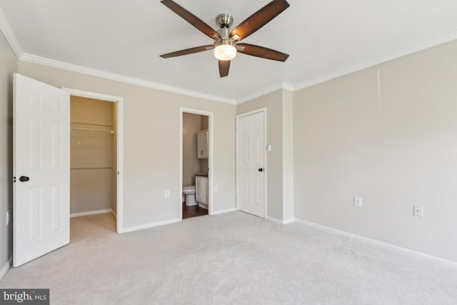 unfurnished bedroom featuring baseboards, ornamental molding, carpet, and a spacious closet