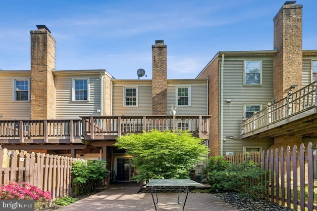 back of house featuring fence, a chimney, and a wooden deck