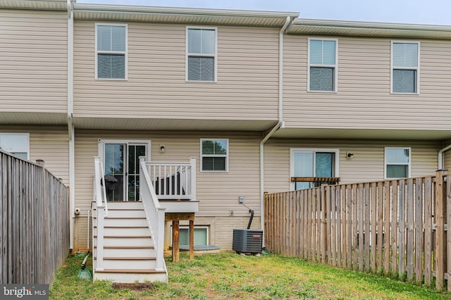 back of property with a fenced backyard, stairs, and central AC