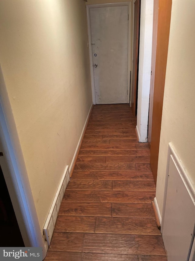 hallway featuring visible vents, dark wood-style flooring, and baseboards