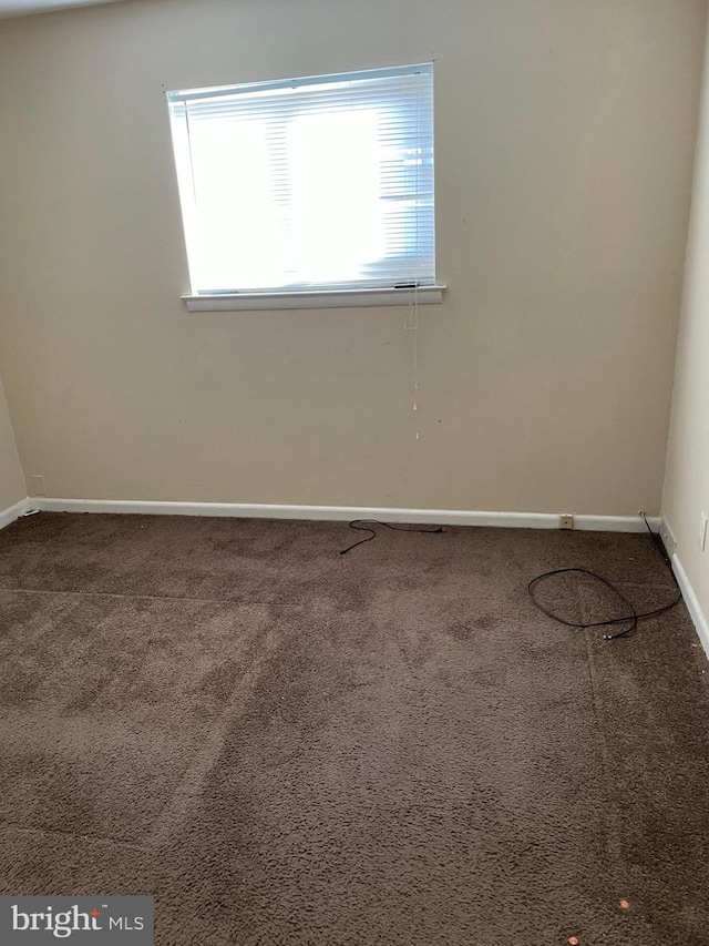 carpeted spare room featuring baseboards and plenty of natural light